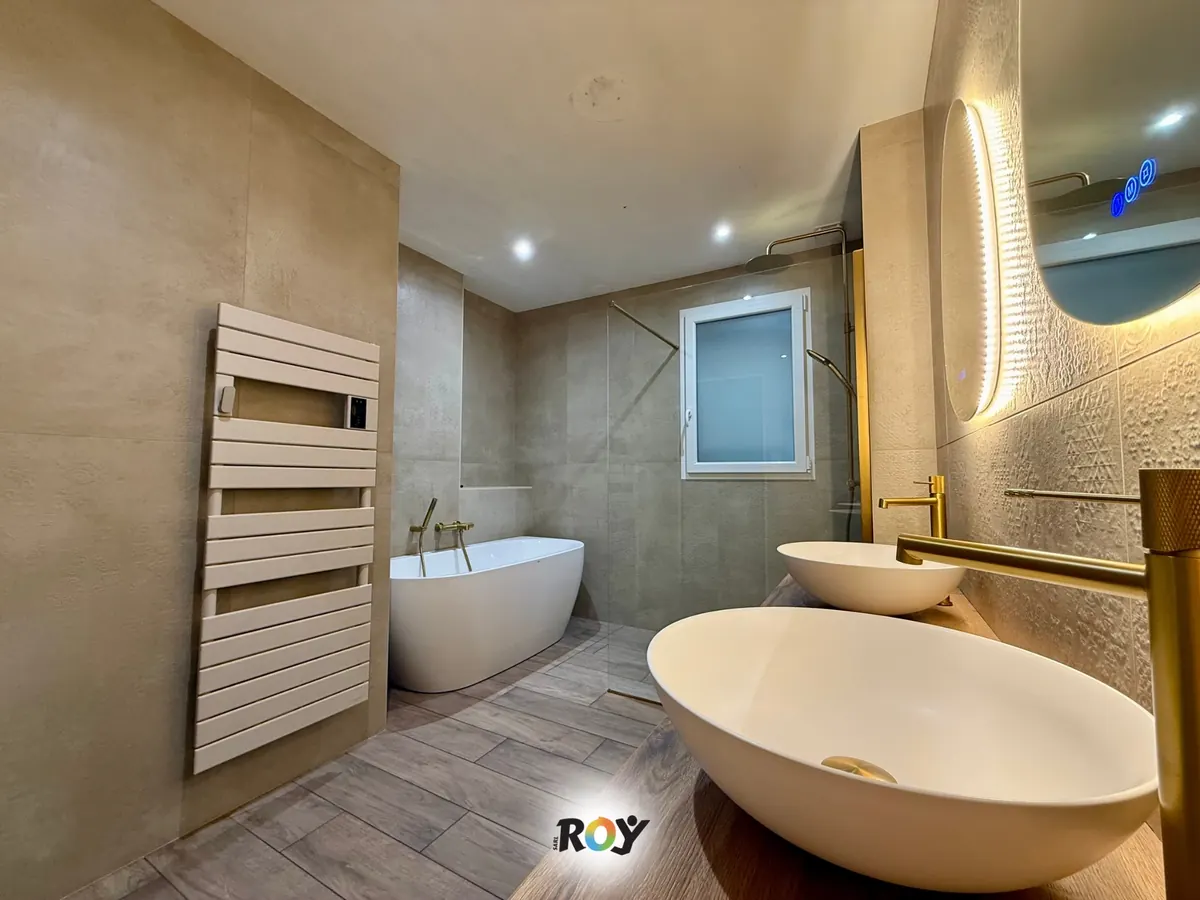 Salle de bain carrelée par nos équipes à Viennay : grands carreaux aux murs, sol effet parquet, baignoire îlot