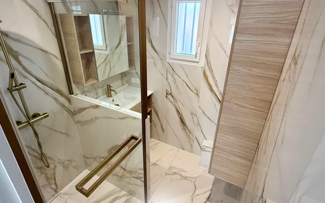 Grand format effet marbre au sol et aux murs d'une douche, posé par nos équipes