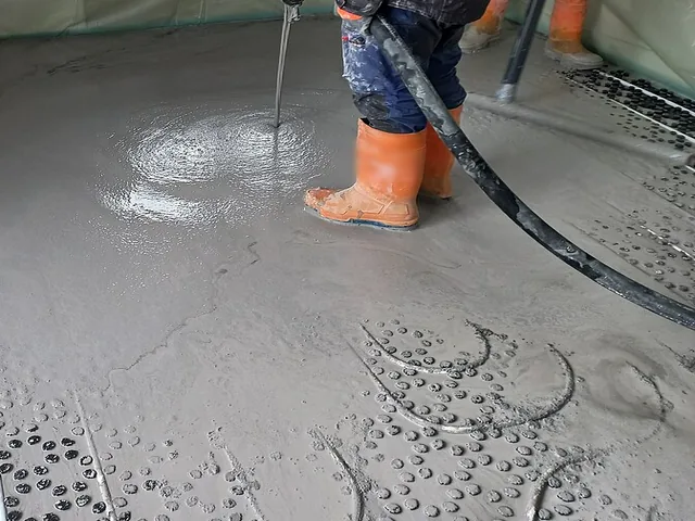 Le tuyau de la pompe déverse la chape liquide, qui s'étale en nappe sur le plancher chauffant