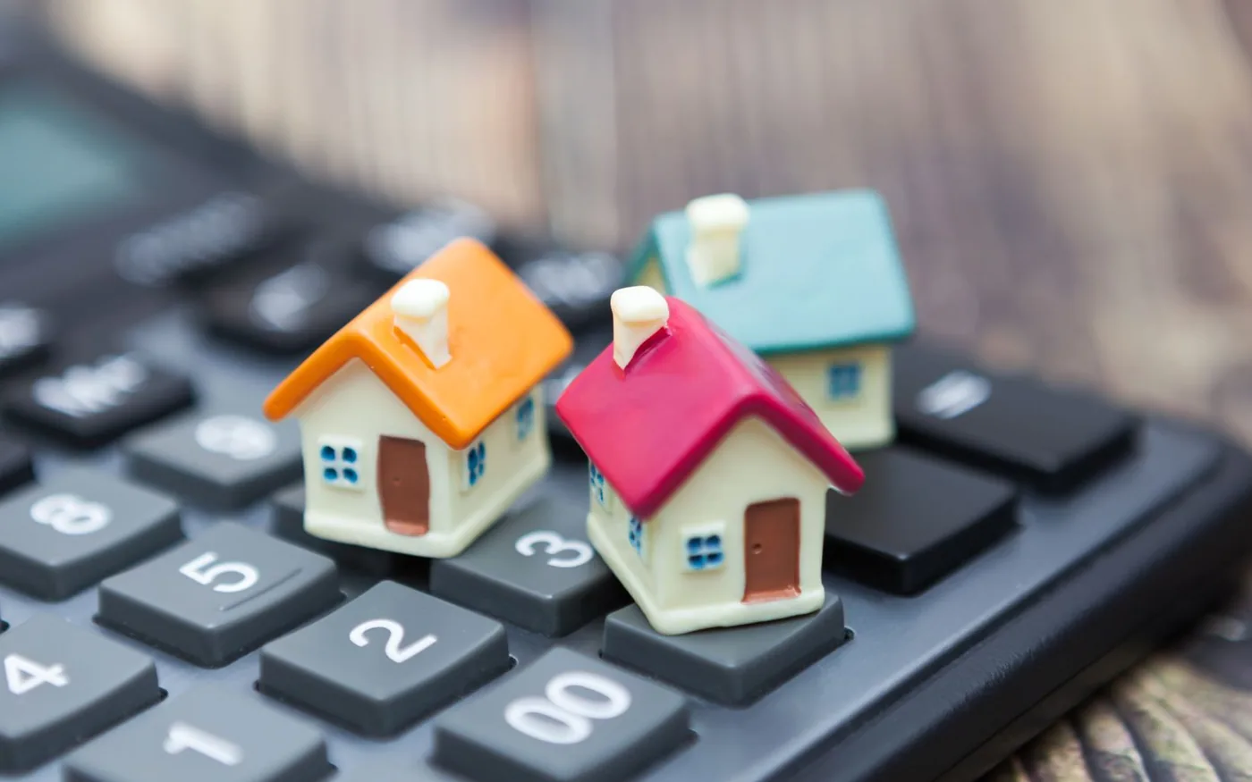 Petites maisons posées sur une calculatrice : le calcul des aides aux travaux