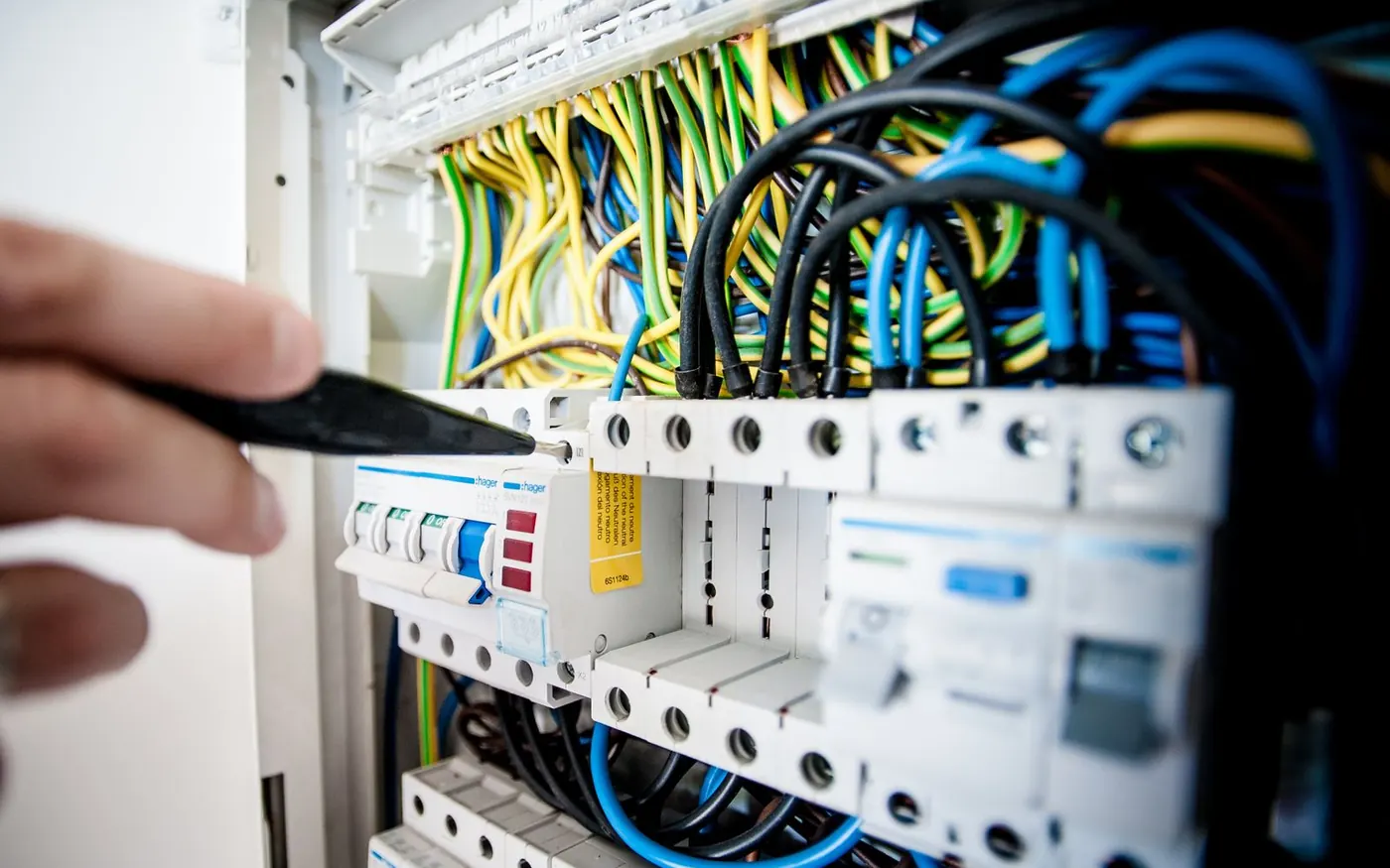 Électricien intervenant au tournevis sur un tableau électrique