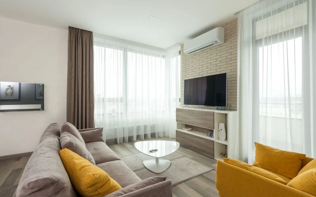 Salon moderne avec une unité de climatisation murale (système split) au-dessus du meuble TV