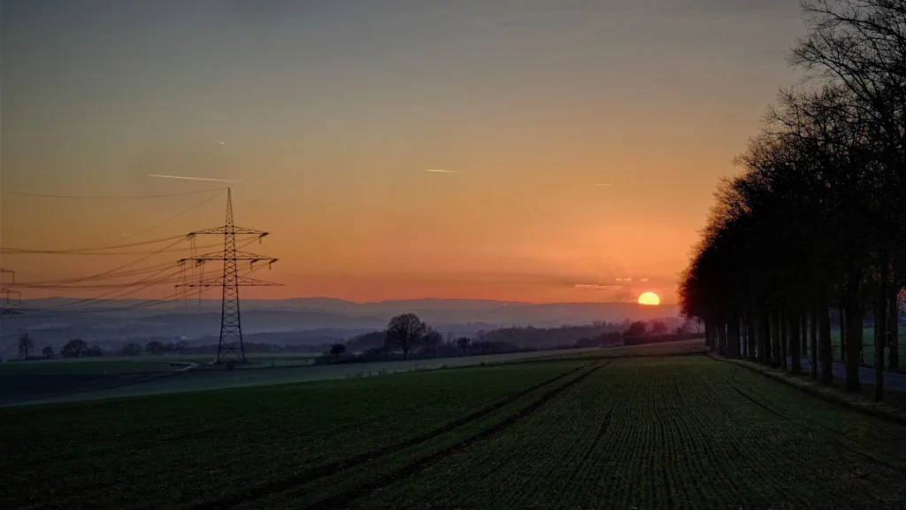 Ligne électrique traversant un champ en Deux-Sèvres au coucher du soleil