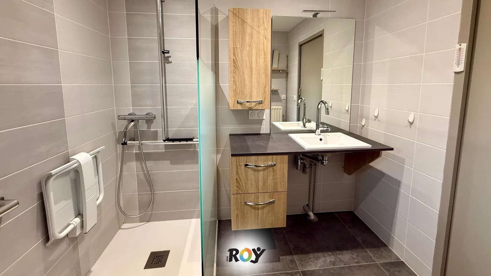 Douche sans baignoire dans une salle d'eau refaite : receveur, siège rabattable, barre d'appui, mitigeur thermostatique